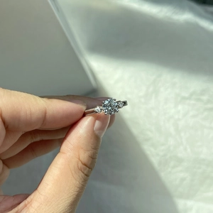 Macro shot of silver three-stone ring with milgrain detailing and sparkling center diamond