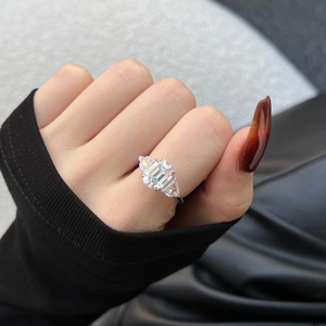 Macro view of three-stone silver ring with large emerald cut stone and pear side gems