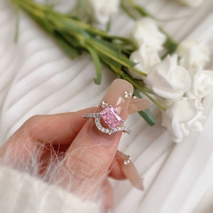 Gros plan d'une bague en argent S925 avec pierre rose et anneau pavé ondulé