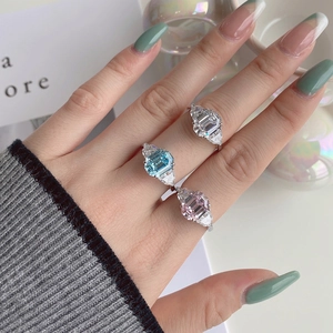 Three emerald-cut zircon rings in white, blue, and pink on model hand for wedding