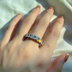 Close-up of S925 sterling silver ring with emerald-cut cubic zirconia on silk fabric