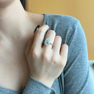 Close-up of a pear-cut silver ring with pavé-set diamonds on a model hand