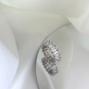 Macro shot of silver eternity ring with emerald cut cubic zirconia on silk background