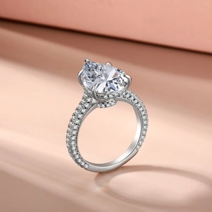 Macro side view of sparkling teardrop-shaped halo ring with pavé-set silver band