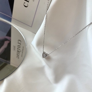 Detail of S925 sterling silver heart necklace with zircon pendant on silk background