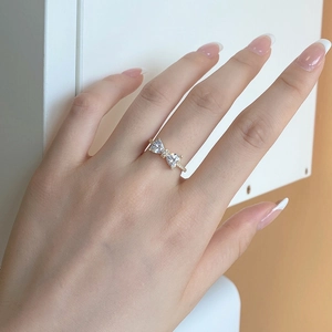 Detailed close-up of a gold bow ring featuring two heart-shaped zircons on a hand