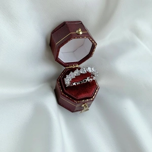 Close-up of heart-cut diamond eternity ring in a red velvet box on white silk fabric