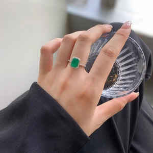 Detail of S925 silver ring featuring emerald cut green zircon with a halo setting