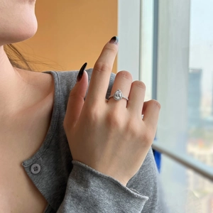 Detailed view of a pear-shaped cubic zirconia ring on finger with halo setting