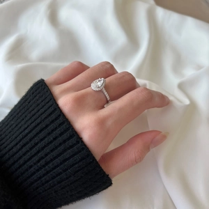 Close-up of a pear-shaped diamond halo ring in S925 silver worn on a finger