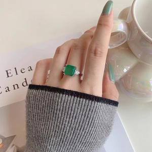 Elegant emerald cut green zircon ring with side diamonds worn on a hand
