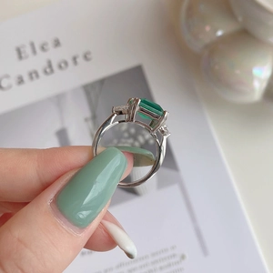 Detailed close-up of emerald-cut green stone ring with marquise-cut side zircons