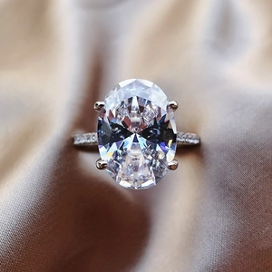 Macro shot of large oval-cut cubic zirconia ring with micro-pave band on champagne silk