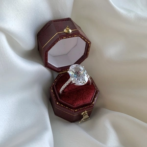 Macro view of large oval zircon silver ring displayed in a red velvet jewelry box