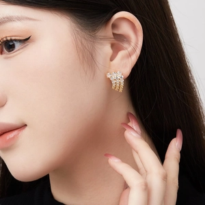 Elegante goldene Flügel-Ohrringe mit Quasten und Zirkonia-Steinen von einem Model getragen