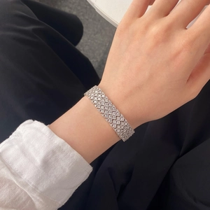 Close-up of a wide sparkling silver tennis bracelet with rows of brilliant white stones