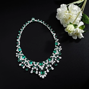 Macro shot of silver luxury necklace featuring emerald stones and white zircon details