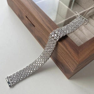 Detailed close-up of wide multi-row cubic zirconia tennis bracelet on a luxury wooden box