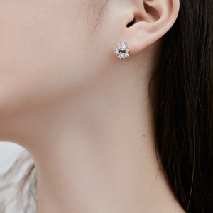 Gros plan de boucles d'oreilles fleurs en argent S925 avec zircons brillants sur l'oreille