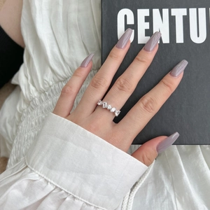 Bague en argent S925 avec zircon asymétrique portée sur fond de tissu blanc plissé