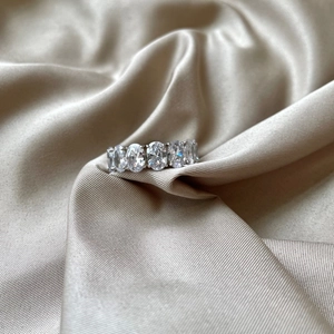 Détail d'une bague en argent S925 avec pierres ovales serties sur du satin couleur champagne