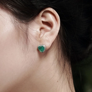 Détail d'une boucle d'oreille cœur en émeraude et zircon sur l'oreille en argent S925