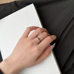 Close-up of minimalist black enamel ring with micro-set zircons on woman's finger