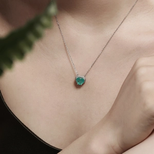Détail du collier coeur en argent S925 avec zircon émeraude sur le cou d'un modèle