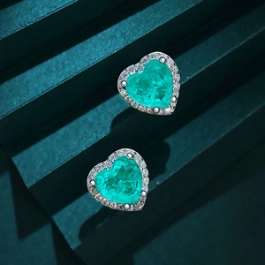 Vue macro de boucles d'oreilles cœur en argent S925 avec pierres bleu-vert et zircons