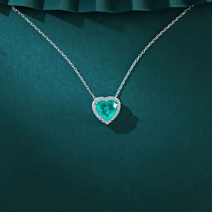 Gros plan du collier coeur en argent avec pierre vert émeraude et sertissage halo brillant
