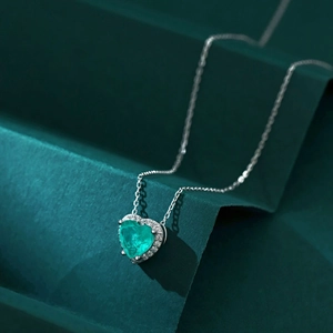 Détail macro d'un pendentif cœur en émeraude avec des zircons blancs scintillants