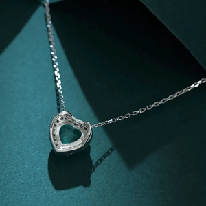 Macro d'un collier en argent S925 avec zircon émeraude en cœur et pavage de diamants
