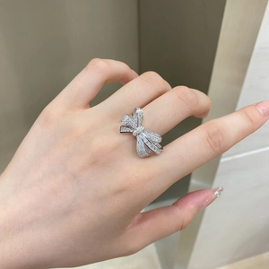 Sparkling S925 silver bow ring with zircon pavé setting worn on a woman's finger
