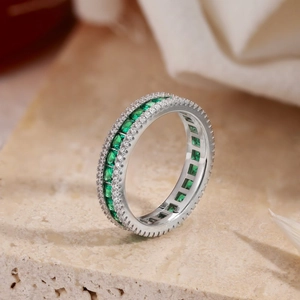 Macro shot of silver ring with square-cut green stones and micro-pave white diamonds