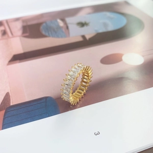 Close-up of golden eternity ring with baguette-cut zircon stones on magazine background