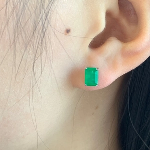 Close-up of S925 sterling silver stud earrings with emerald-cut green zircon on ear