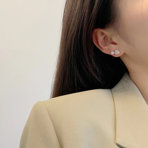 Detail of S925 sterling silver heart earrings with zircon on woman's earlobe