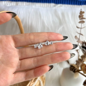 Detailed close-up of heart-shaped zircon earrings in S925 sterling silver held by hand