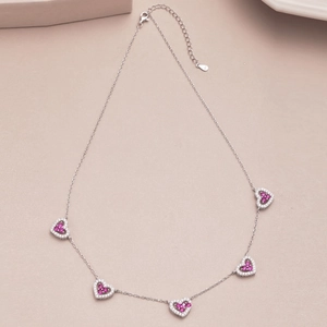 Macro detail of S925 sterling silver chain with heart charms and pink purple stones