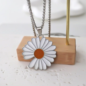 Collana con ciondolo a margherita con petali bianchi e centro arancione su legno