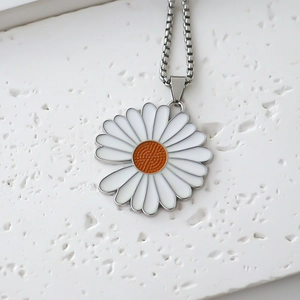 Vista macro dettagliata di un ciondolo a margherita con petali in smalto bianco su catena