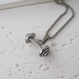 Détail macro du pendentif haltère en acier inoxydable argenté sur chaîne box