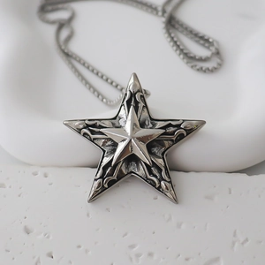 Detail of vintage silver star pendant with intricate floral engravings and a layered 3D star