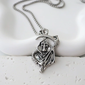 Detailed view of antique silver Grim Reaper pendant on a beaded chain necklace