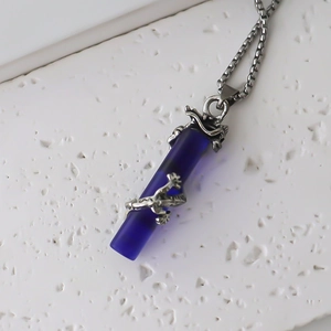 Vue détaillée d'un pendentif dragon bleu enroulé avec une chaîne en argent élégante
