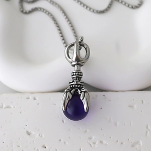 Detail of vintage claw pendant with deep purple gem and silver chain necklace