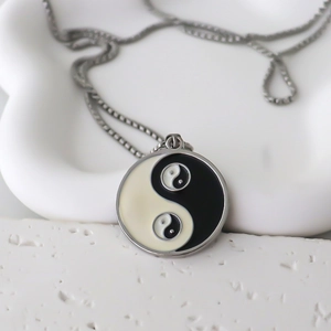 Close-up of circular Tai Chi Yin Yang pendant with small nested detail on silver box chain