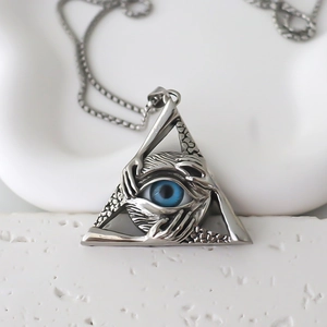 Close-up of Eye of Horus triangle pendant with blue pupil on white stone background