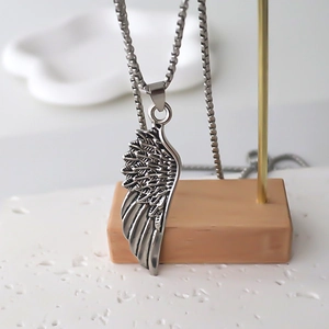Vintage silver feather pendant necklace for men and women on a minimalist wood display