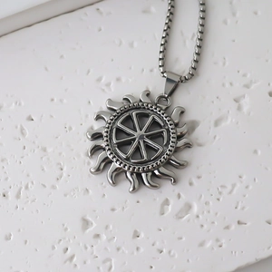 Macro du pendentif roue solaire Kolovrat en acier inoxydable sur fond de pierre blanche